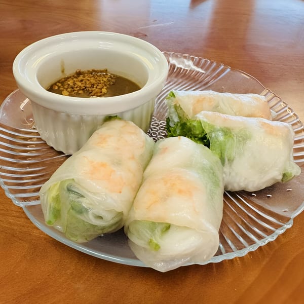 Four fresh Vietnamese spring rolls with shrimp and lettuce, served with peanut dipping sauce.